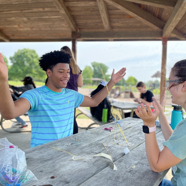 Two students on a picnic table working on a project.
