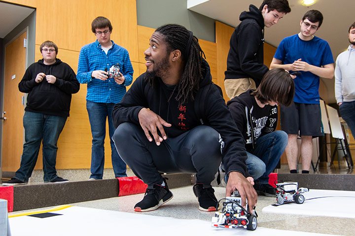 Students gathered using a mechanical device on the ground.
