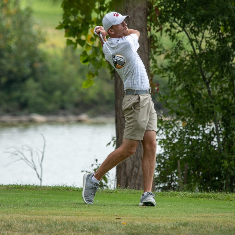 student athlete swinging a golf club.