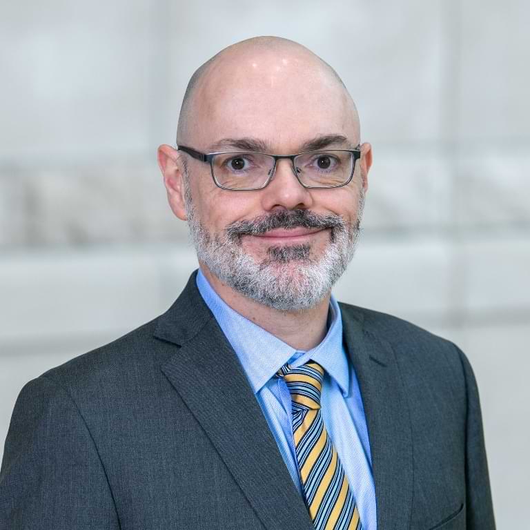 Headshot of Scott Jones wearing glasses in a suit.