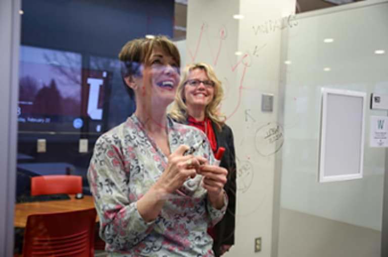 two faculty looking looking a a clearboard.